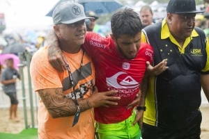 Filipe Toledo a sair da água com muita dor, ajudado pelo pai e um segurança da prova.